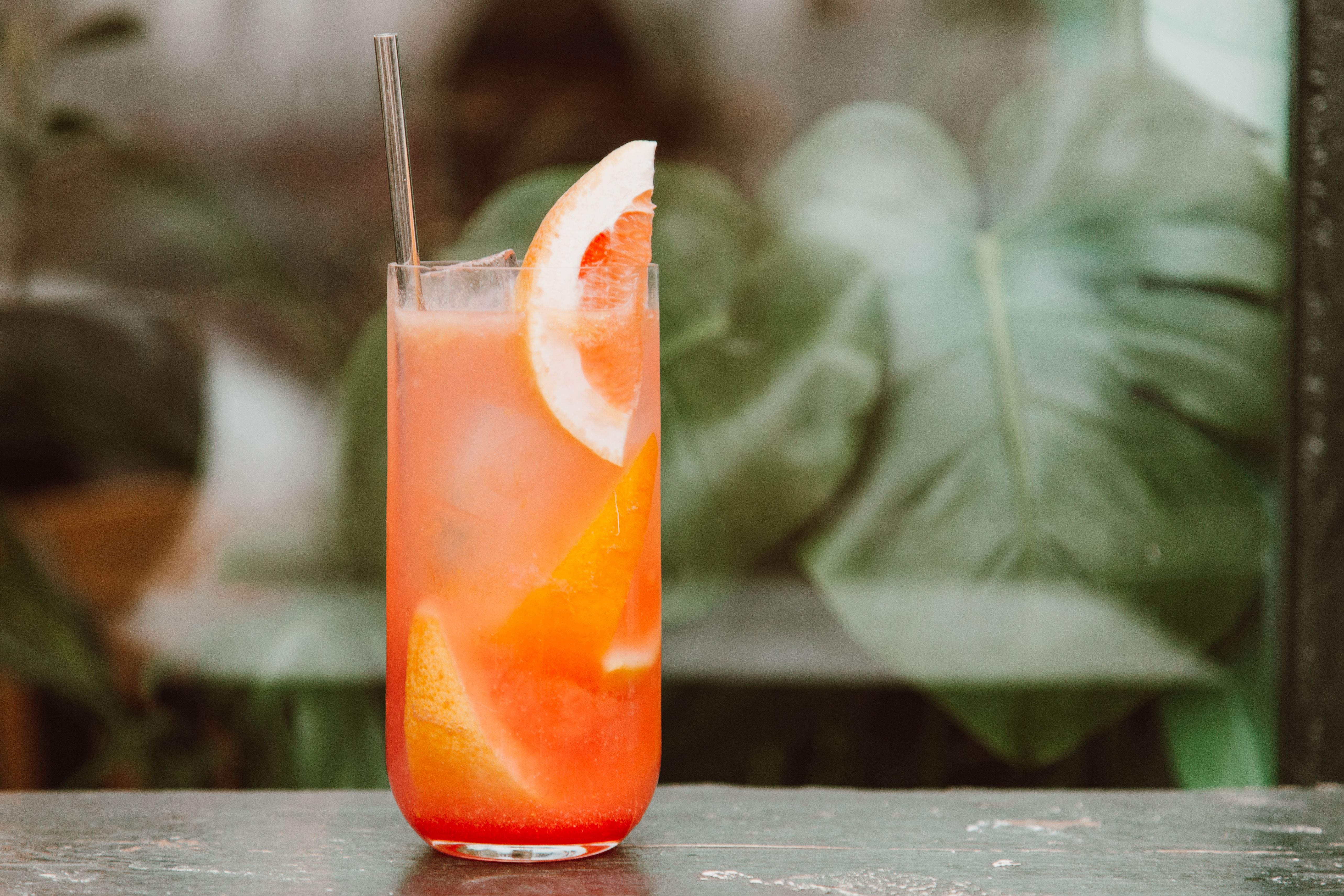 Unbranded pink grapefruit drink with ice against a leafy background